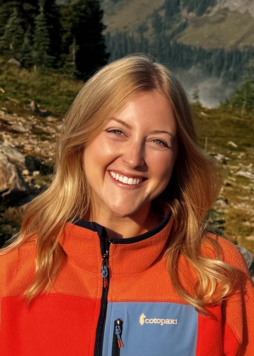 Person wearing a red jacket with a blue patch in a mountainous landscape