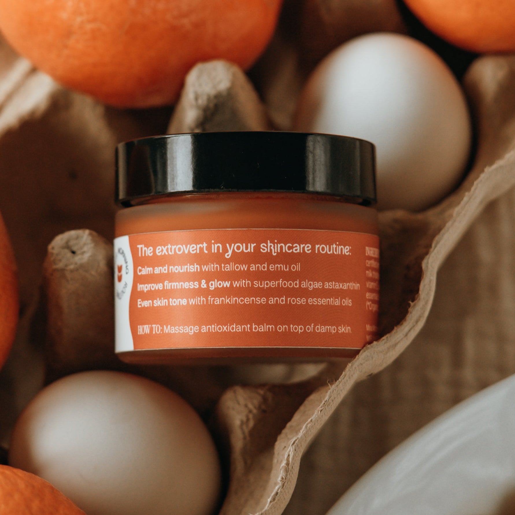 Jar of skincare product with oranges, eggs, and cereal on a wooden surface