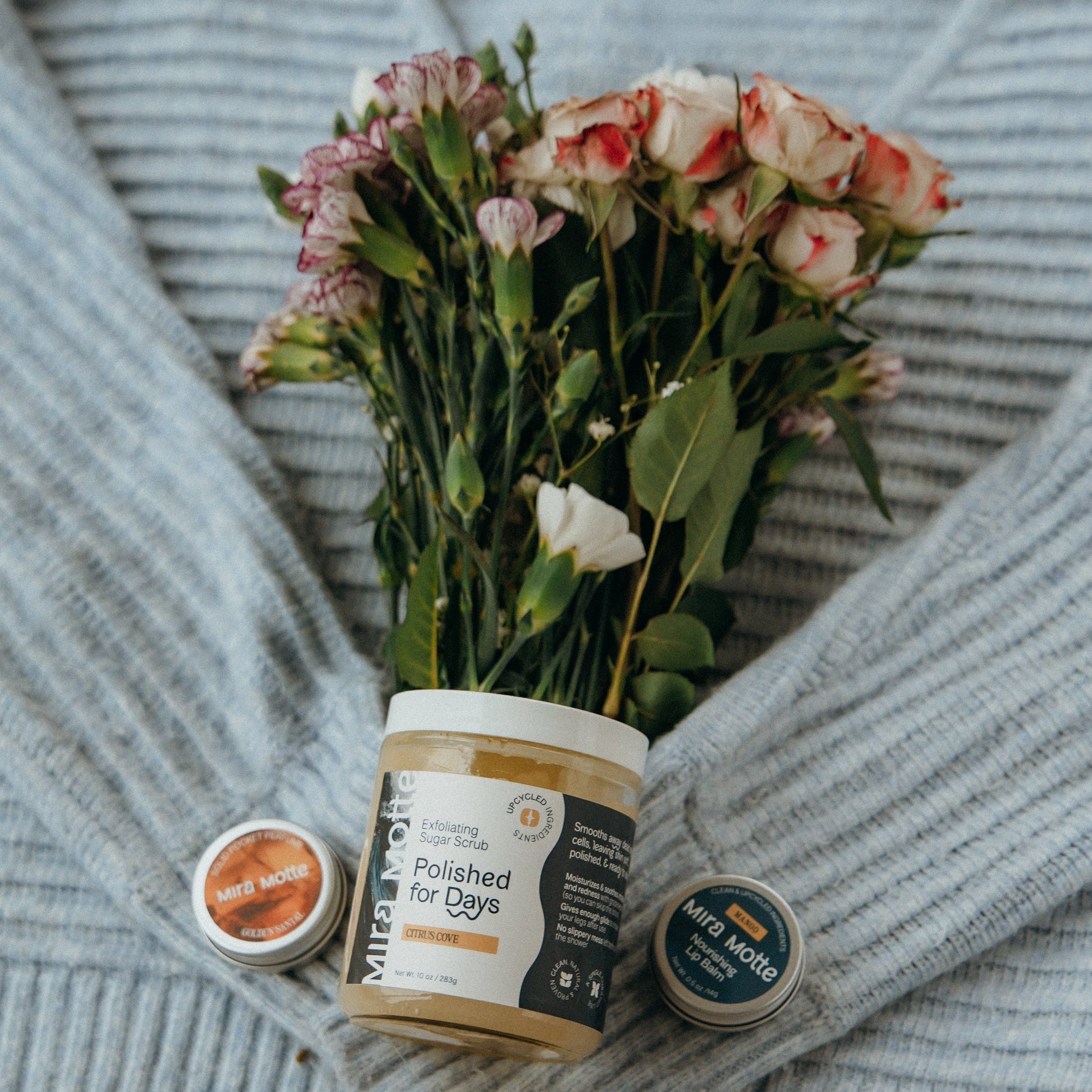 Gray sweater with a bouquet of flowers and a jar on a wooden surface