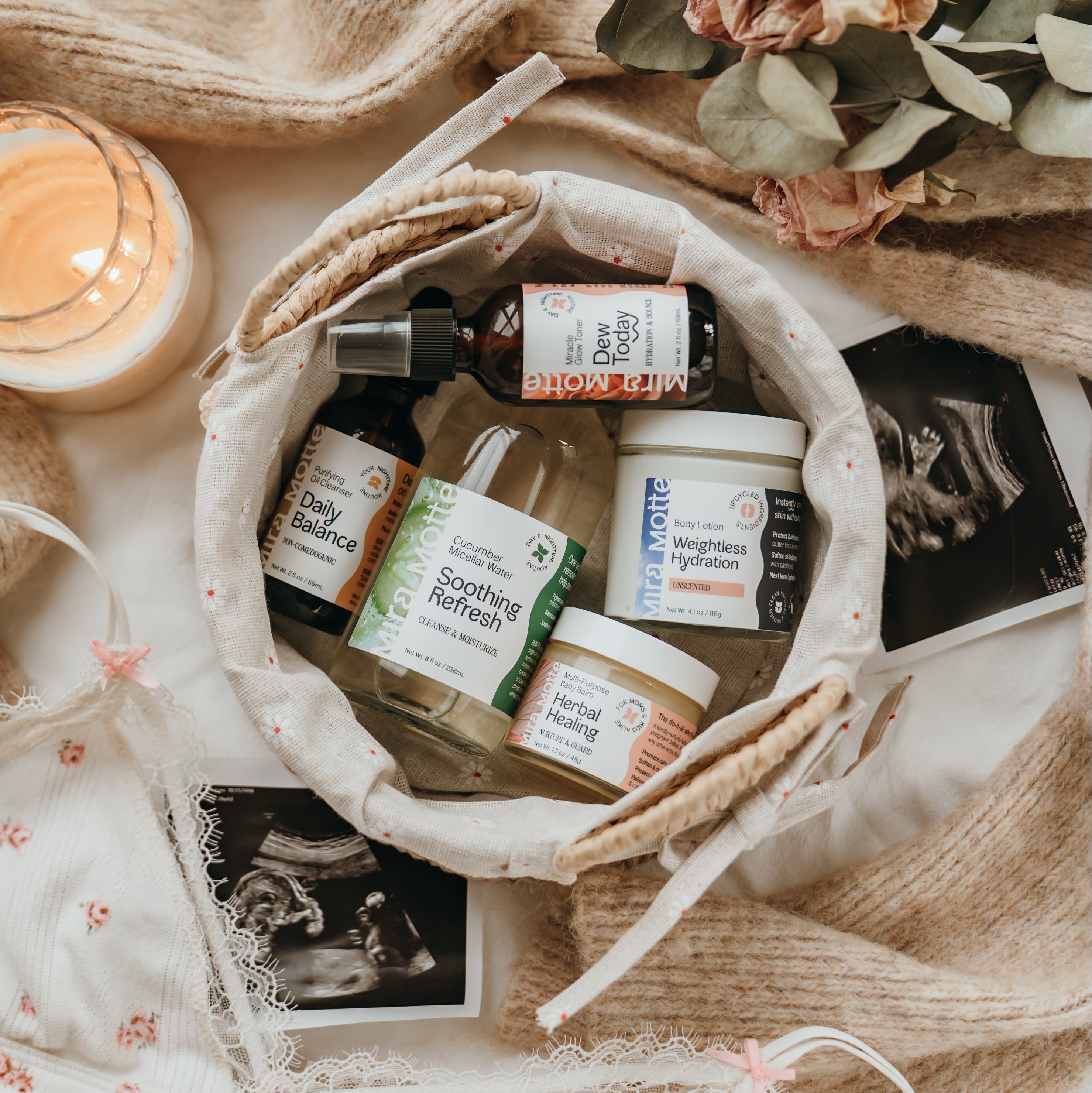 Basket of skincare products, a candle, and flowers on a soft surface