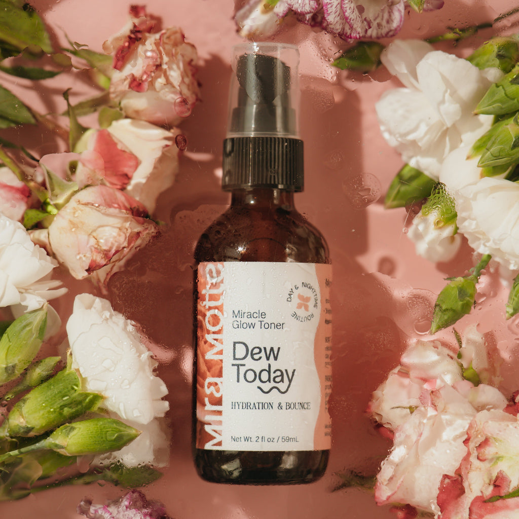 Bottle of 'Dew Today' toner surrounded by flowers on a pink background