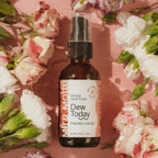 Bottle of 'Dew Today' toner surrounded by flowers on a pink background