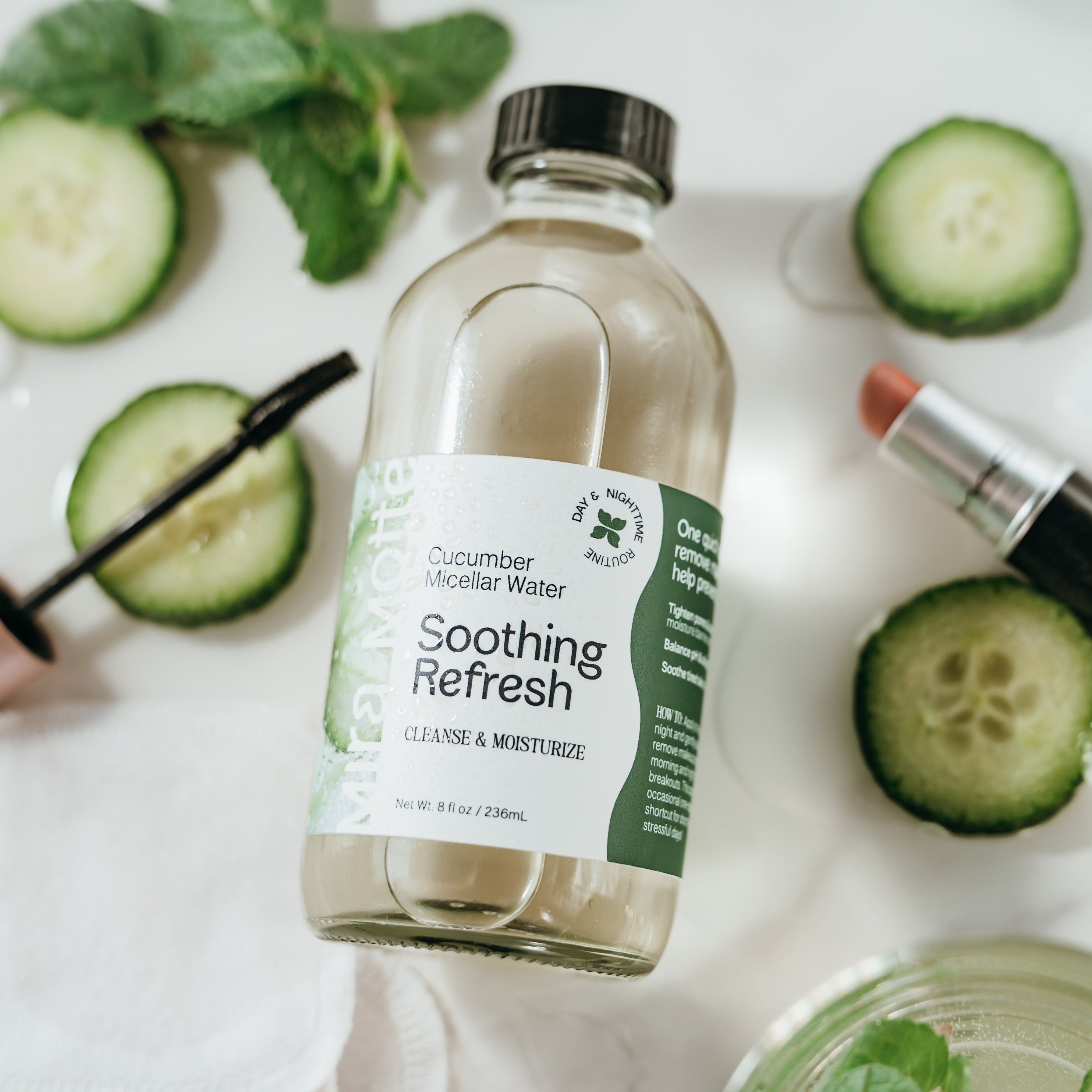 Bottle of 'Soothing Refresh' cucumber micellar water with cucumber slices and a lip balm on a white background.