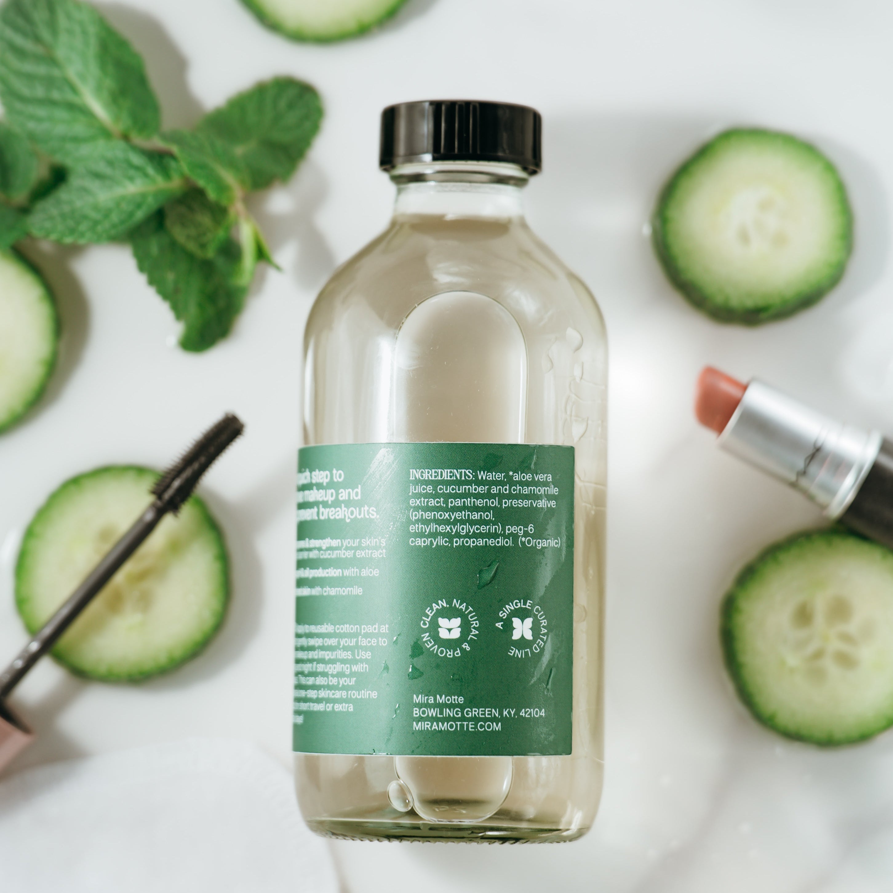 Bottle of MIRA MOTTE micellar water with cucumber slices and a lip balm on a white background