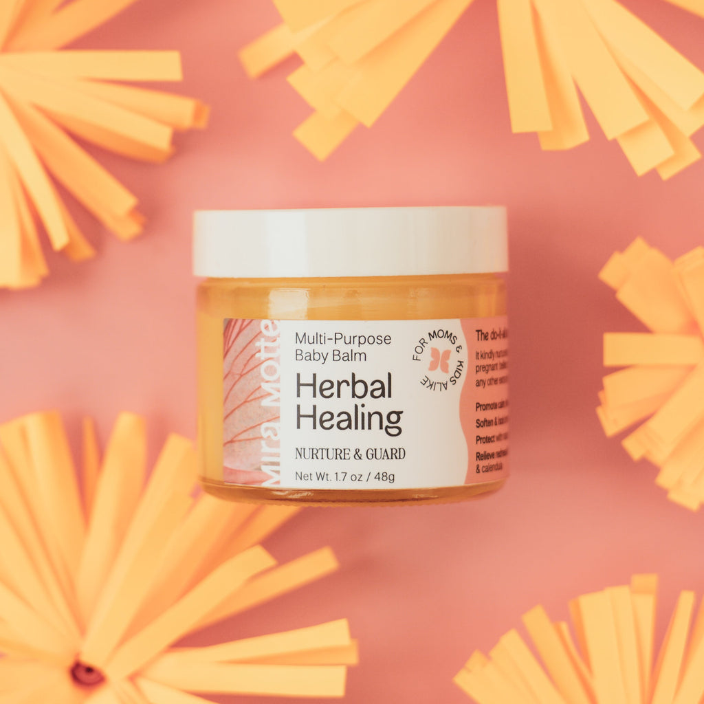 Jar of Herbal Healing balm on a pink background with yellow flowers
