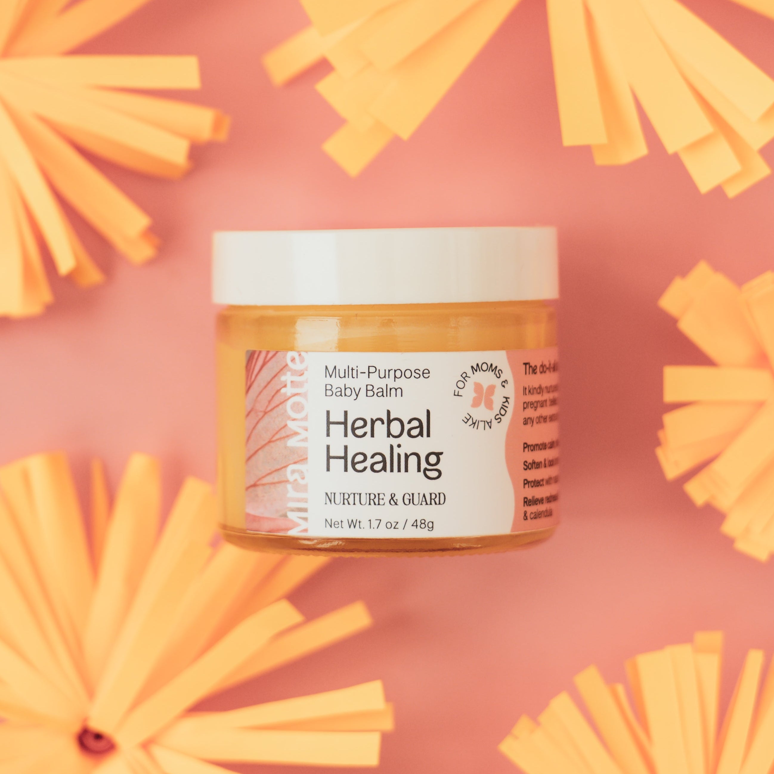 Jar of Herbal Healing balm on a pink background with yellow flowers