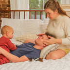 Family of three in a bedroom setting; mom treating dad to a mini facial massage