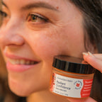 Person holding a jar of 'Radiant Confidence' balm close to their face