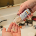 Person holding a container of Kikkoman soy sauce with a sprinkle of seasoning on their palm.