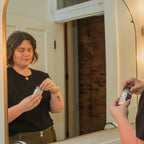 Person applying dry shampoo in front of a mirror